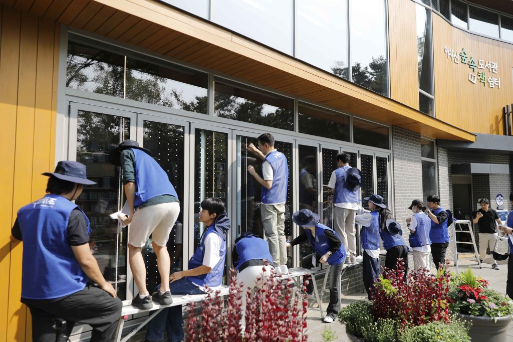 지난해 kcc글라스 임직원과 관계자들이 아차산숲속도서관에 조류충돌방지스티커를 부착하고 있는 모습