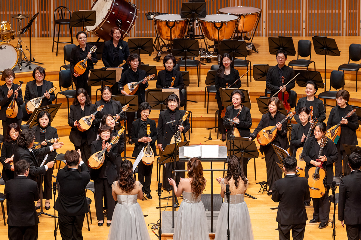 미라클보이스앙상블 단원들이 오케스트라 연주단과 눈을 맞추며 서로를 응원하고 있다, 단원들이 목소리에 희망을 담아 노래하고 있다.